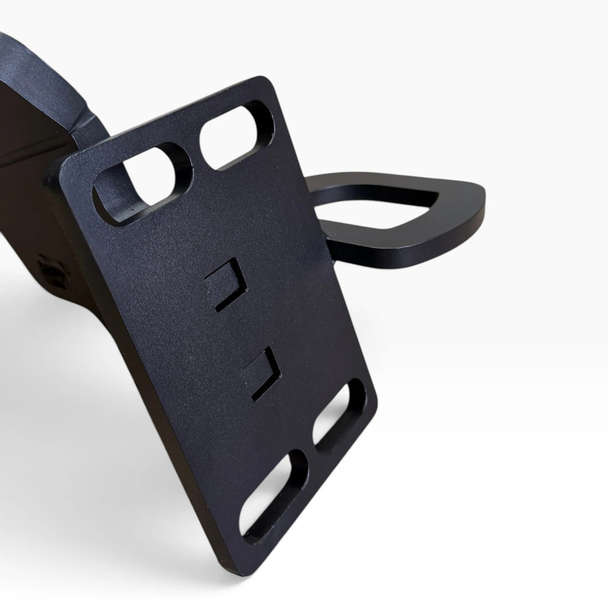 Close-up of a Cascadia deer guard bracket's mounting plate with its four slotted holes and the towing eye