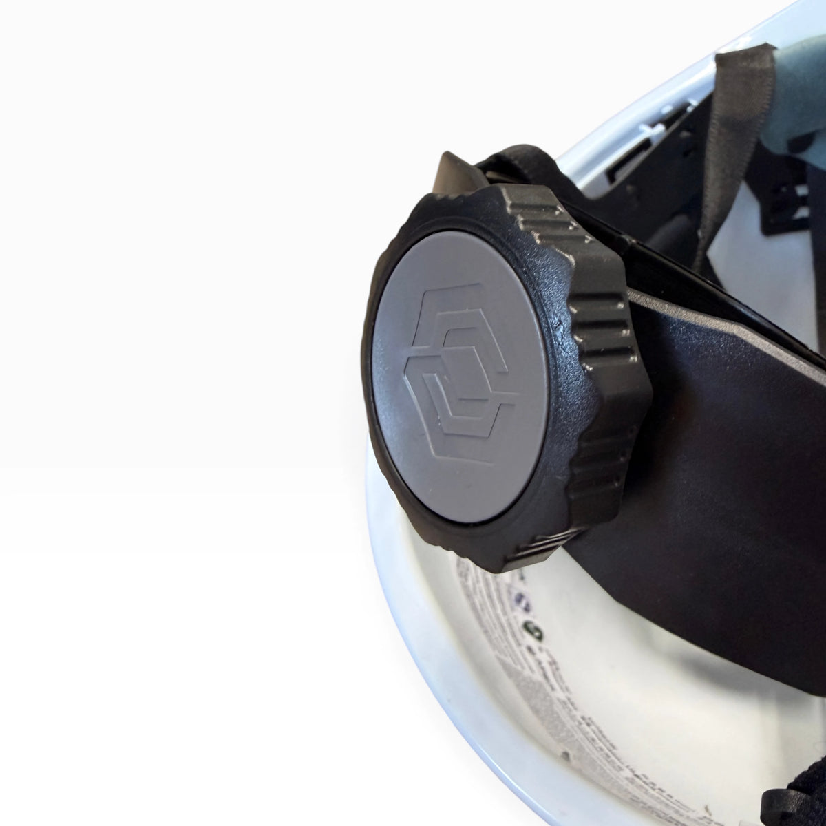 Close-up of the black adjustment knob at the back of the hard hat's suspension, with a hexagon logo on the dial.