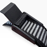 Close-up of the chin strap's toothed lever adjuster, flipped open, with the striped webbing running through it.