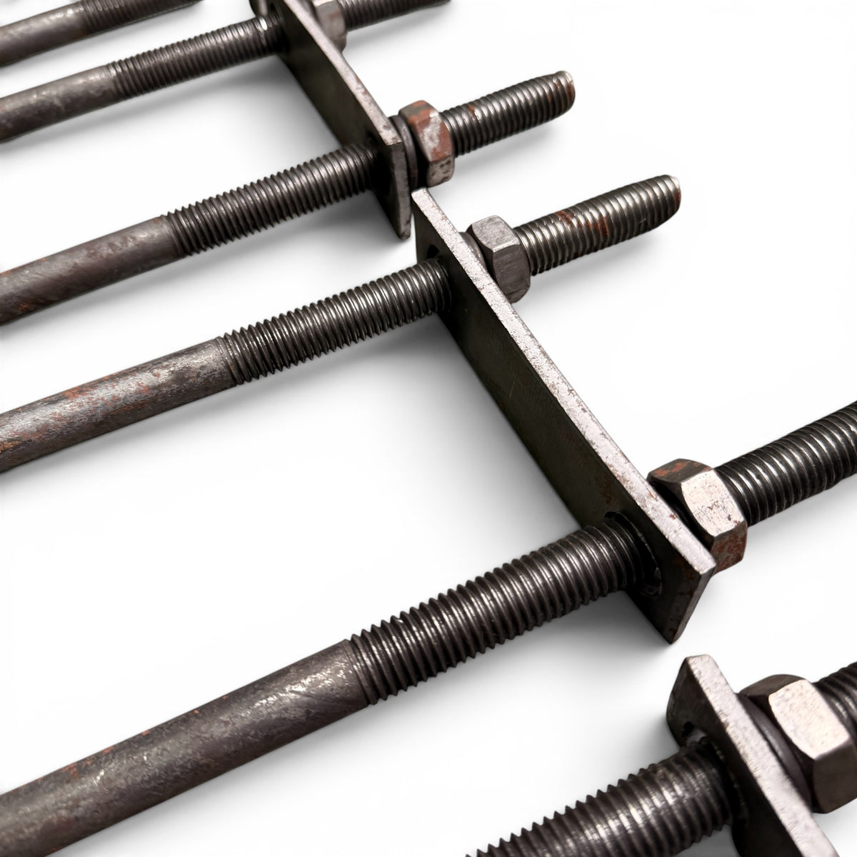Close-up of several U-bolt threaded ends passing through their flat steel mounting plates