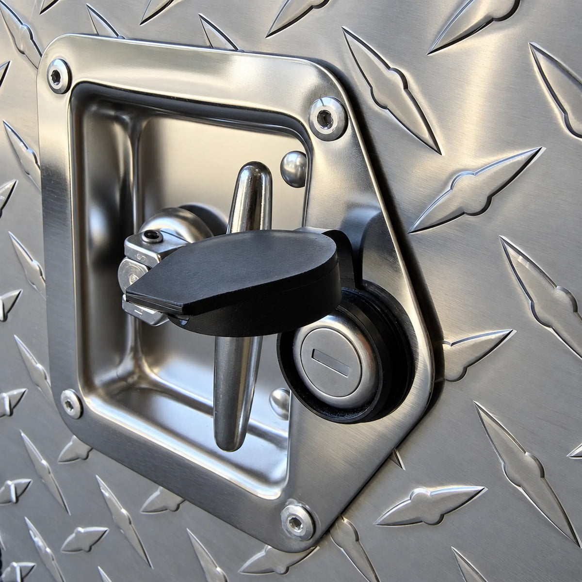 Close-up of a T-lock set in the diamond plate door, its rubber cap open over the key cylinder