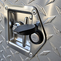 Close-up of a T-lock set in the diamond plate door, its rubber cap open over the key cylinder