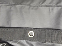 Silver grommet in a band of black webbing, with a double-stitched seam running across the tarp above it
