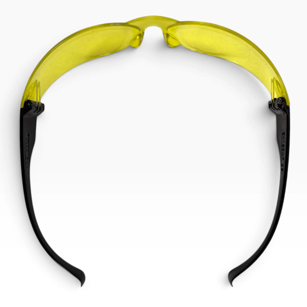 Yellow-lens safety glasses seen from above, nose pads at the center and both black temple arms stretched back.