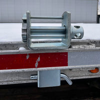 Close-up of the winch mounted in the trailer stake pocket, weld seam visible on the bracket