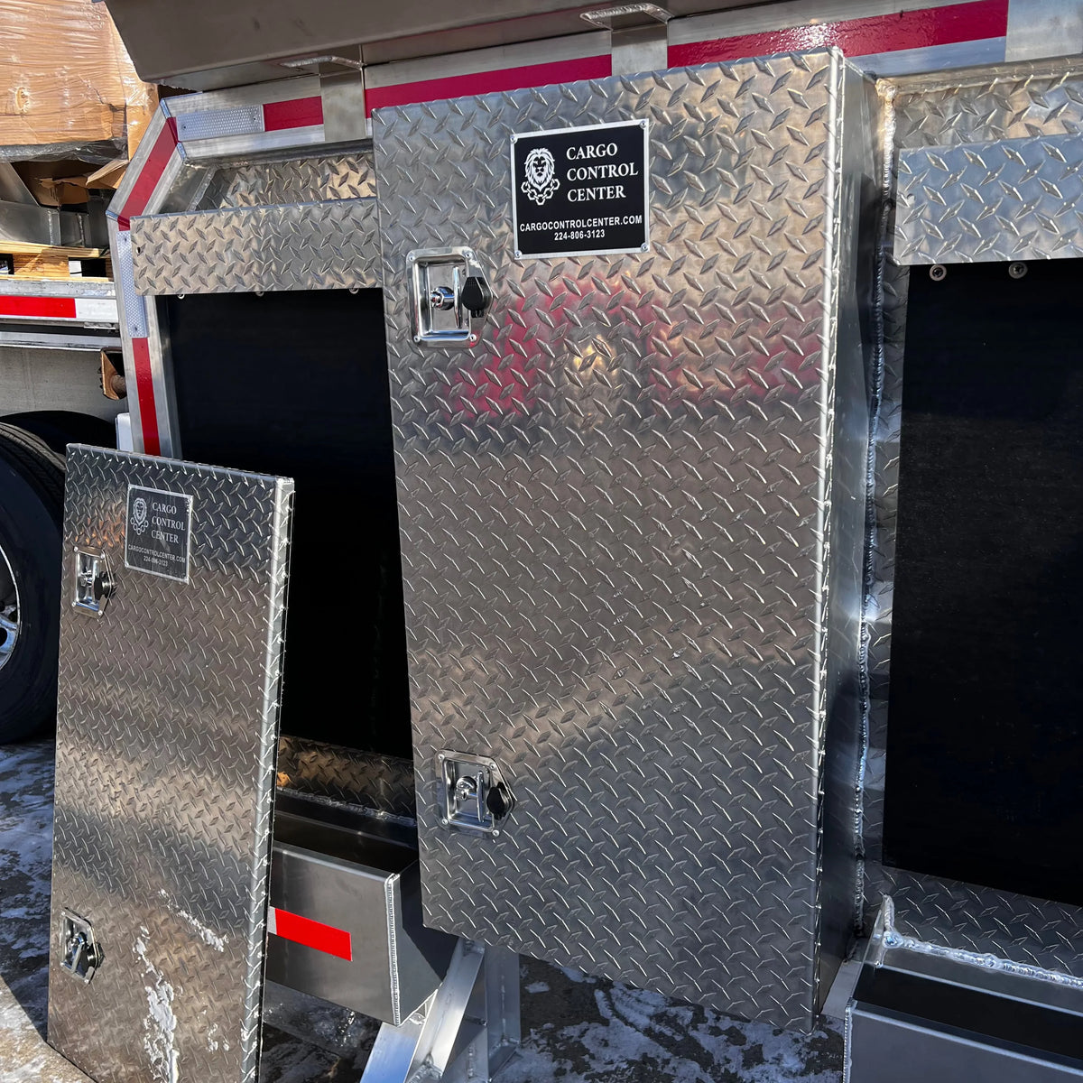 Stainless diamond-plate tool box door shown at an angle with its two paddle latches and mounting plate