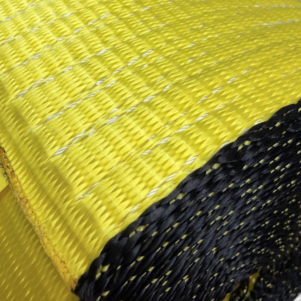 Extreme close-up of the yellow weave with white tracer threads beside the dark coiled layers.
